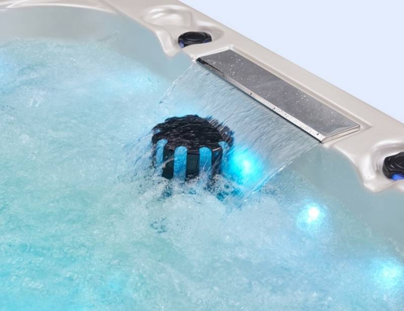 Détail de la cascade et des jets éclairés du spa Dacca – ambiance idéale pour des séances de spa en soirée, en toute saison