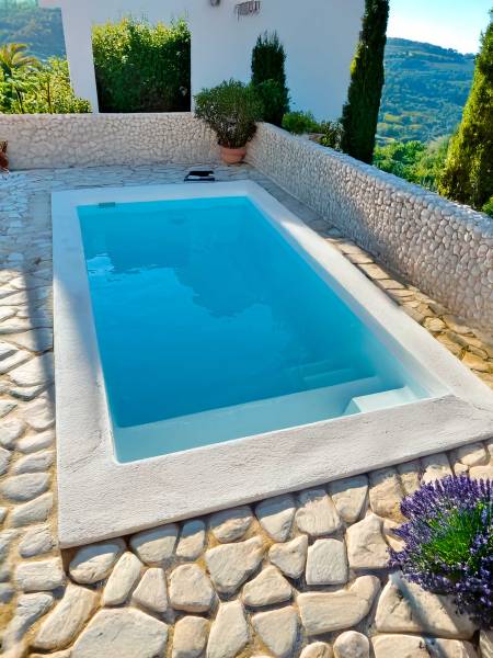 Piscine Bora Bora installée en extérieur avec un aménagement en pierres naturelles et vue dégagée.