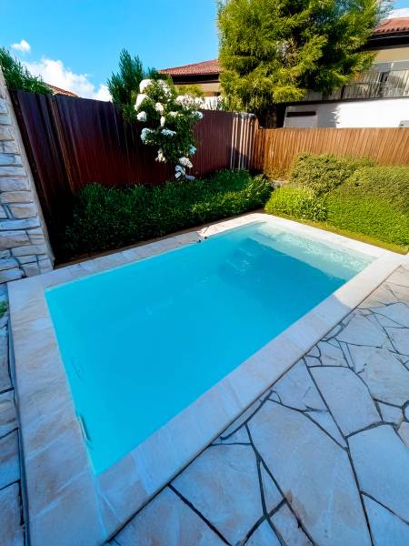 Exemple de pose de la piscine Bora Bora à Six-Fours-les-Plages, parfaitement intégrée dans une cour paysagée.