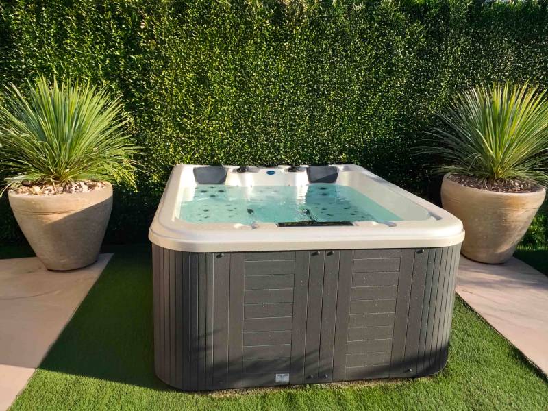 Spa 5 places installé à Sainte-Maxime – Coque blanche marbrée et jupe grise dans un aménagement paysager sobre et moderne